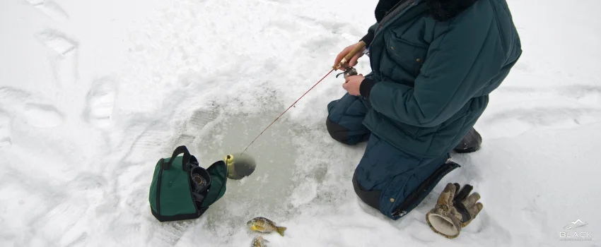 A man fishing from an ice shack.