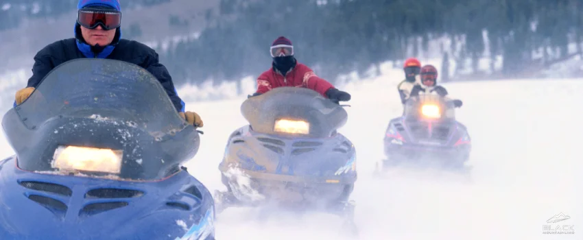 Group of men riding a snowmobile.