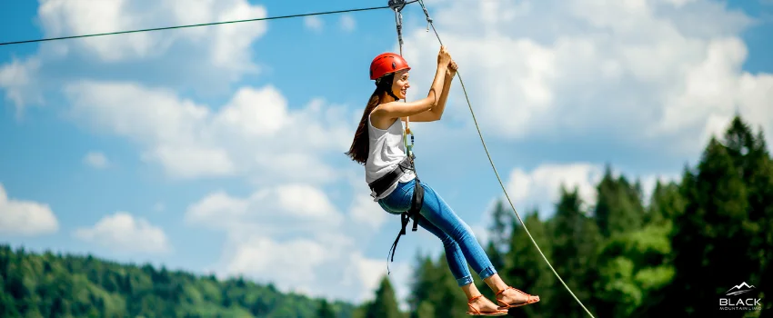 A woman with safety gear riding a zipline.