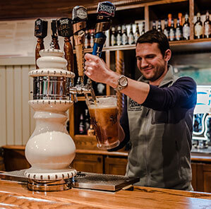 Bartender fills pitcher of beer at tap station.